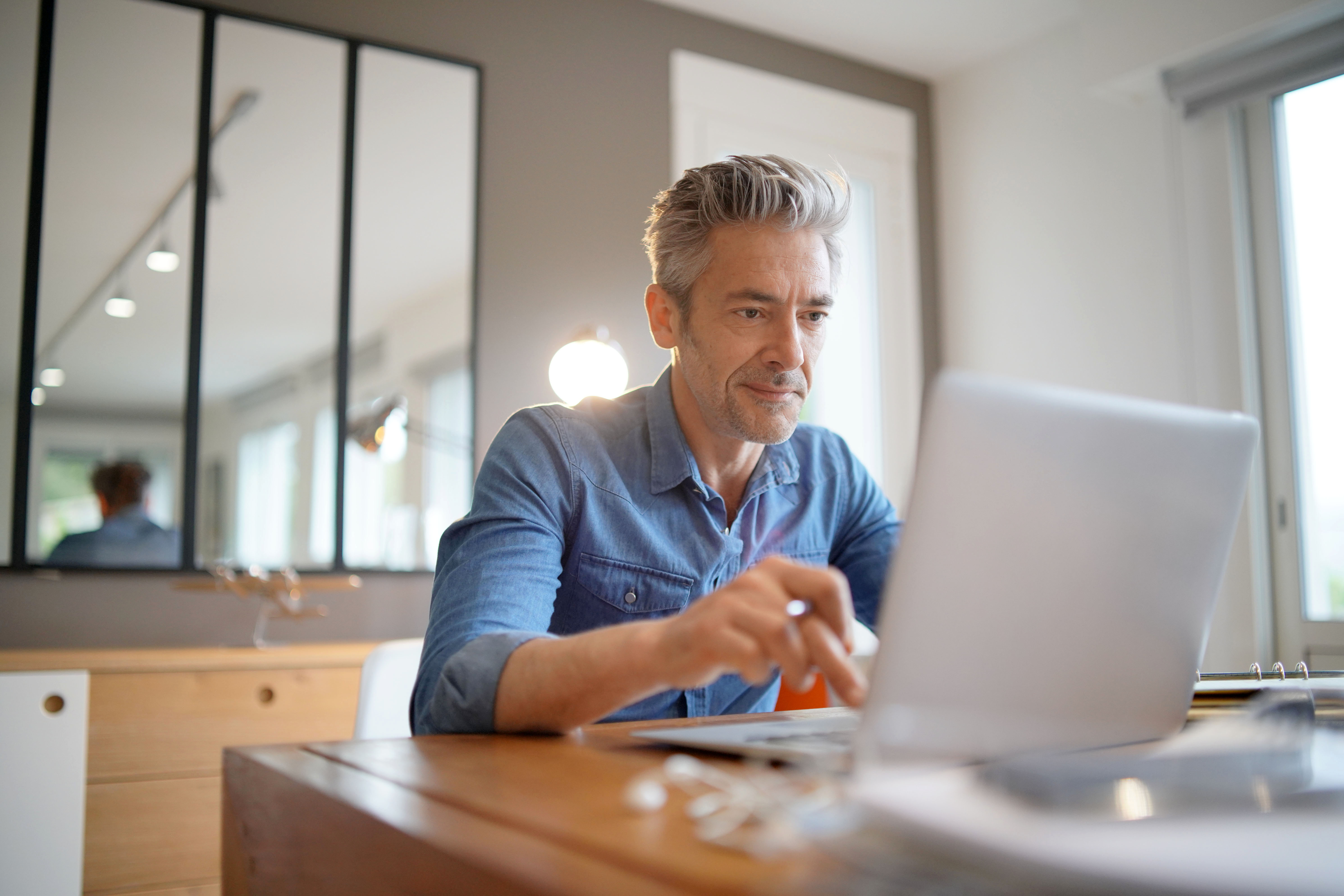 man in his 50s using his laptop at the table
